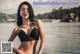 A woman in a black bikini standing on a beach.