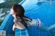 A woman in a bikini laying on the edge of a swimming pool.