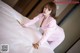A woman in a pink suit standing on a bed.