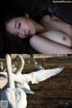 A woman laying on top of a couch next to a group of swans.