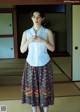 A woman standing in front of a tatami mat in a room.