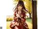 A woman in a red kimono sitting under a tree.