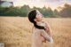 A naked woman standing in a field of tall grass.