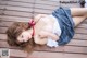 A woman laying on a wooden deck wearing a skirt and a bra.