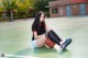 A woman sitting on a basketball court with a ball.