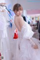 A woman in a wedding dress standing in front of a rack of dresses.