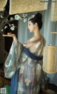 A woman in a blue and white kimono holding a wooden object.