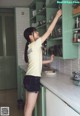 A woman standing in a kitchen reaching for a bowl of food.