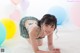 A woman in a bikini laying on a white rug with balloons.